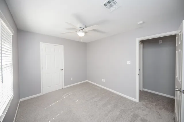 an empty room with a ceiling fan and a window