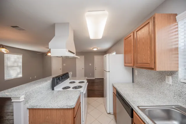 a kitchen with stainless steel appliances granite countertop a sink a stove and a refrigerator