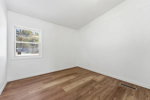 a bed sitting in a bedroom next to a window with potted plant
