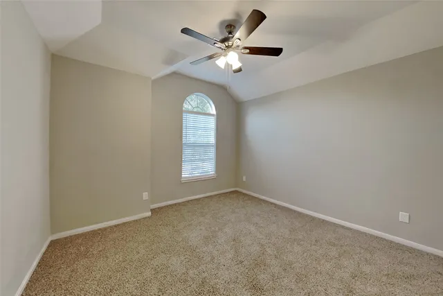 an empty room with a ceiling fan and window
