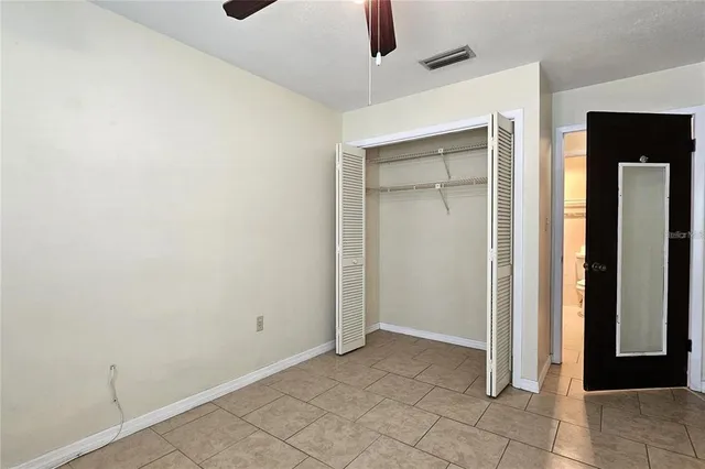an empty room with closet and a chandelier fan
