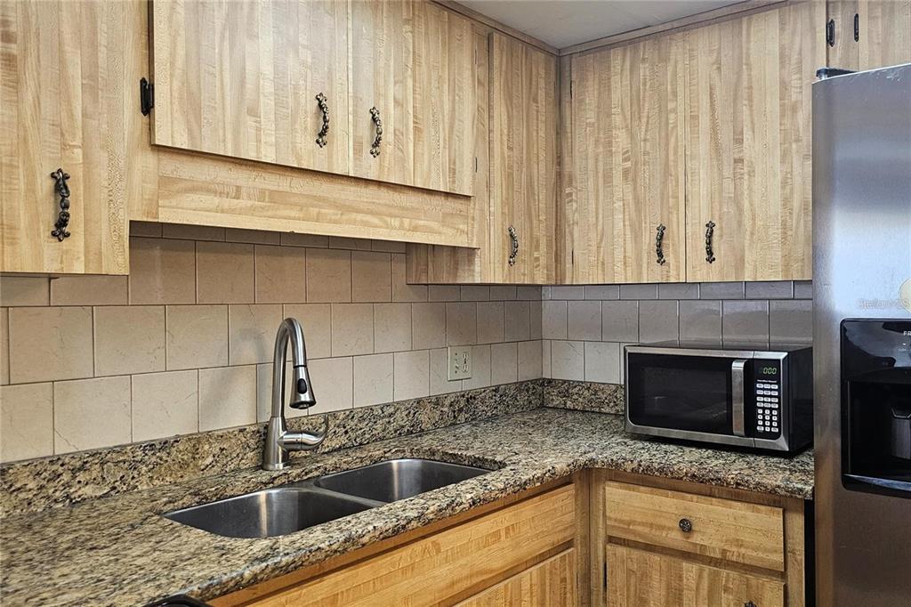 4330 Tahitian Gardens Circle, Unit C Holiday, FL 34691 - Photo 7 of 20 a kitchen with granite countertop a sink stainless steel appliances and cabinets