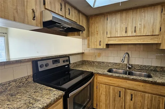 a kitchen with granite countertop a stove sink and cabinets