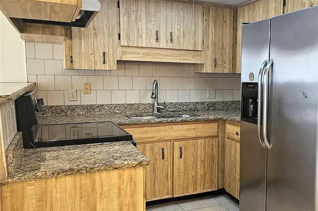 a kitchen with stainless steel appliances granite countertop a sink a refrigerator and a granite counter tops