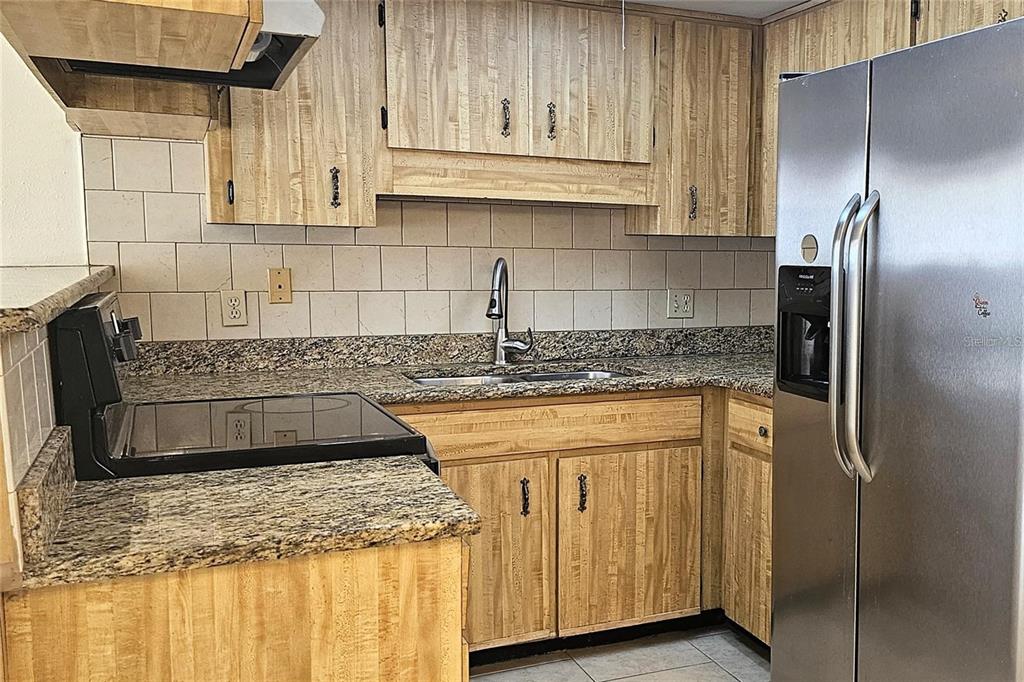 4330 Tahitian Gardens Circle, Unit C Holiday, FL 34691 - Photo 9 of 20 a kitchen with stainless steel appliances granite countertop a sink a refrigerator and a granite counter tops