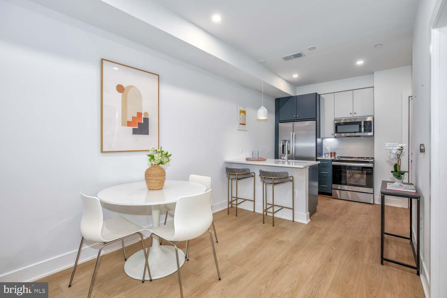 2310 4th Street Northeast, Unit FIVE Washington, DC 20002 - Photo 5 of 19 a kitchen with stainless steel appliances kitchen island granite countertop a dining table chairs and granite counter tops