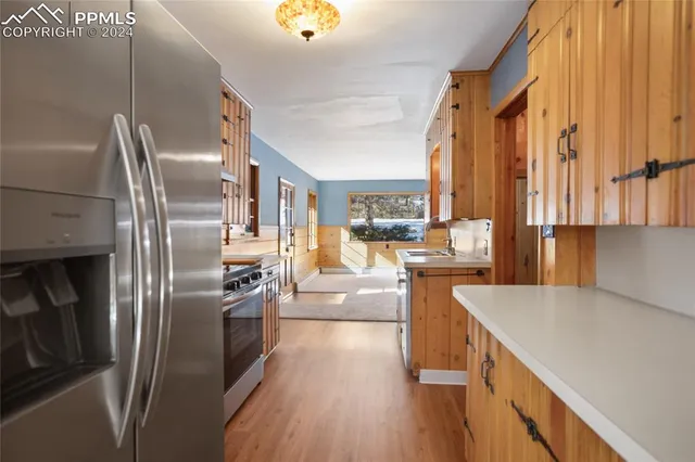 a kitchen with stainless steel appliances a refrigerator sink and wooden floor