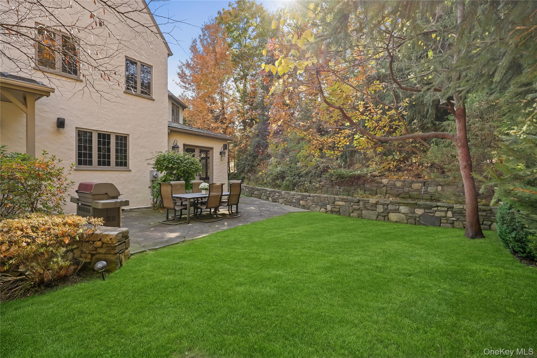 15 Carstensen Road Scarsdale, NY 10583 - Photo 25 of 35 a view of a backyard with table and chairs potted plants and a large tree