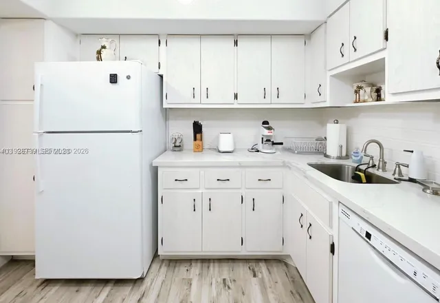 a white refrigerator freezer sitting inside of a kitchen with white cabinets