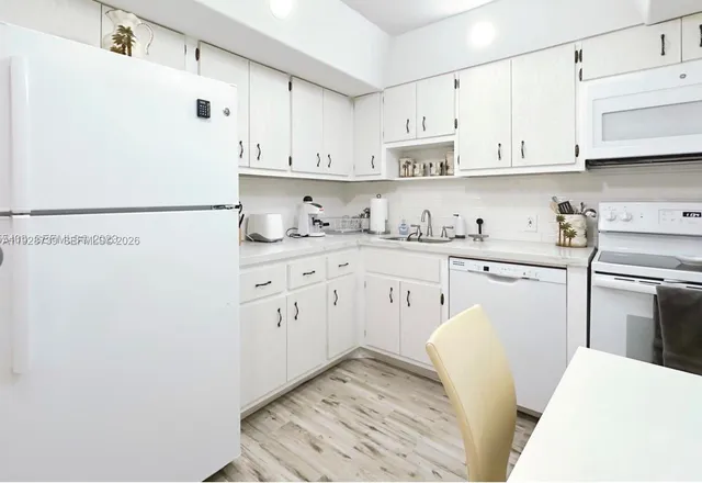 a kitchen with stainless steel appliances white cabinets and wooden floors