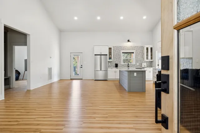 a view of a kitchen with kitchen island a sink stainless steel appliances counter space and wooden floor