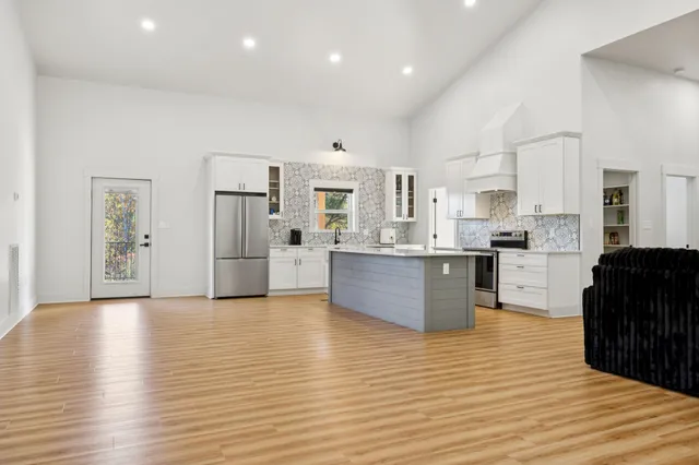 a large kitchen with stainless steel appliances granite countertop a stove a sink dishwasher and a refrigerator with wooden floor