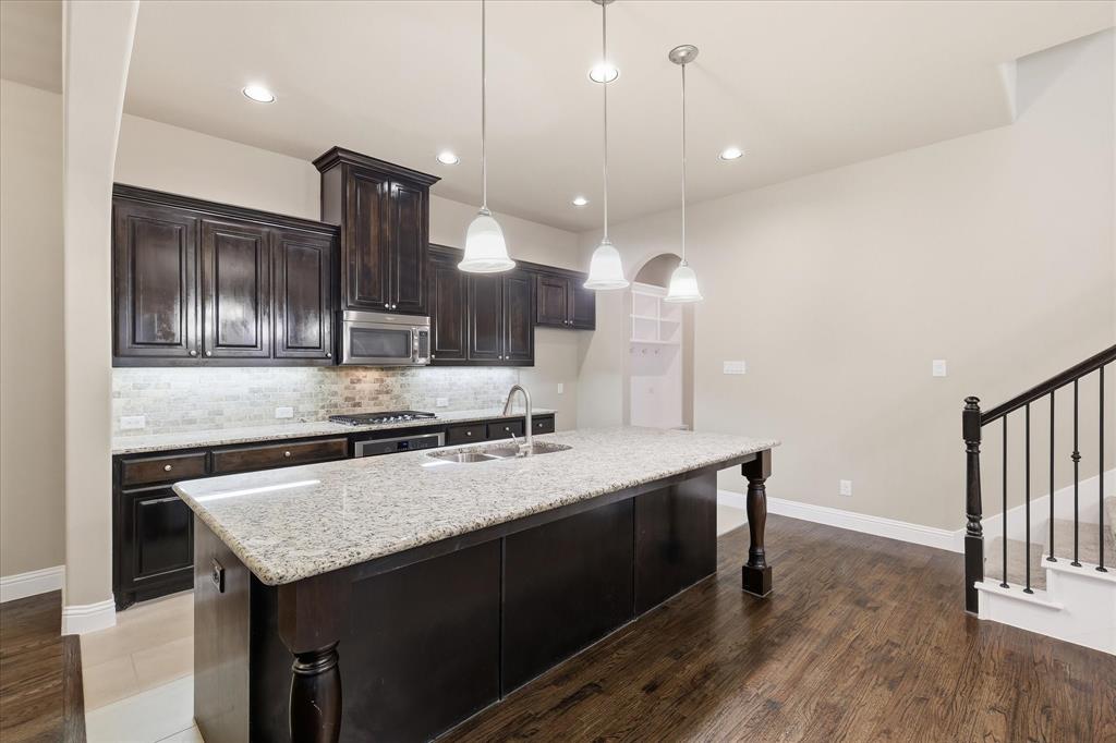 768 Huntingdon Street Coppell, TX 75019 - Photo 3 of 37 The kitchen offers granite countertops, dark stained cabinetry, stainless appliances, tile backsplash, and an oversized island ideal for meal prep or casual seating.