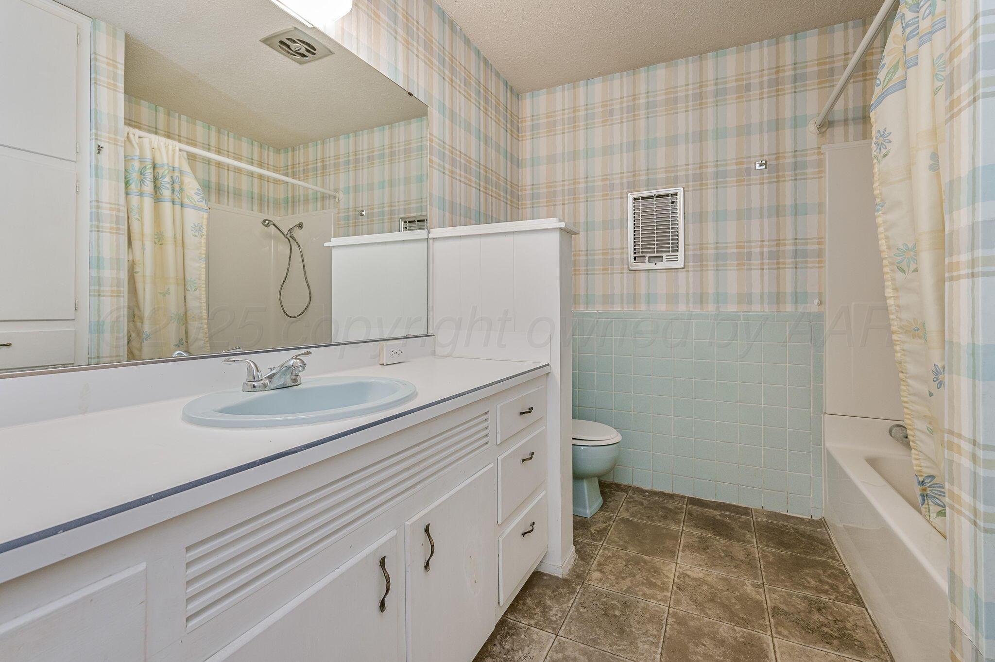 4701 Mesa Circle Amarillo, TX 79109 - Photo 17 of 20 a bathroom with a granite countertop sink a toilet and shower