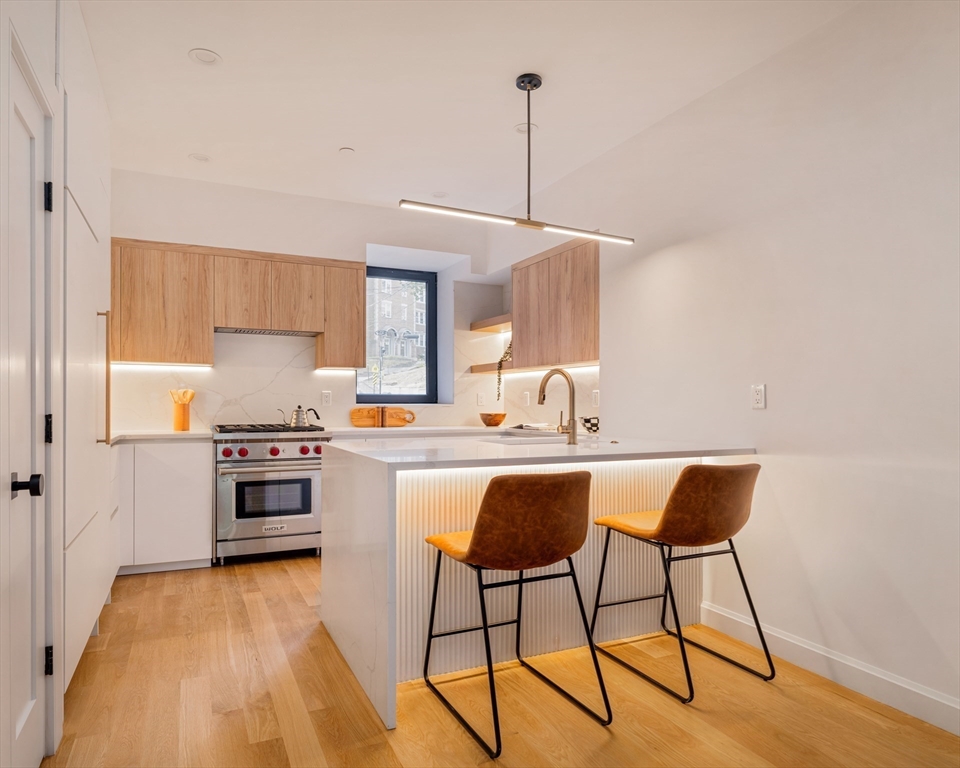 1618 Beacon Street, Unit 1 Brookline, MA 02446 - Photo 7 of 29 a kitchen with stainless steel appliances granite countertop a stove top oven a sink dishwasher and white cabinets with wooden floor