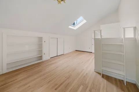 an empty room with wooden floor closet and windows