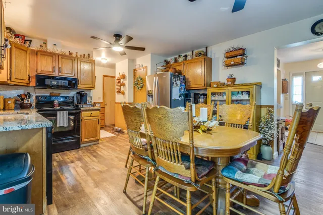 a dining room with stainless steel appliances kitchen island granite countertop a table chairs and a refrigerator