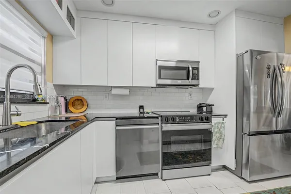 a kitchen with stainless steel appliances granite countertop a refrigerator and a stove top oven