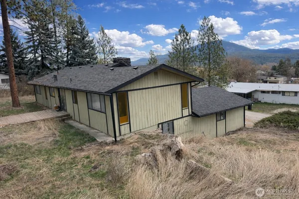 a view of a house with a yard plants and large tree