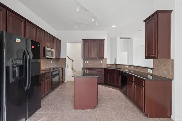 a large kitchen with stainless steel appliances granite countertop a stove a refrigerator a sink a oven and wooden cabinets