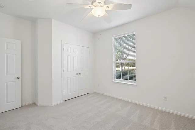 an empty room with chandelier fan and windows