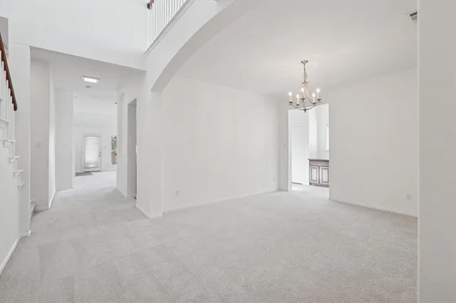 a view of an empty room and chandelier fan