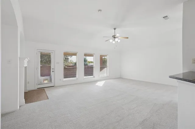 a view of an empty room with chandelier fan