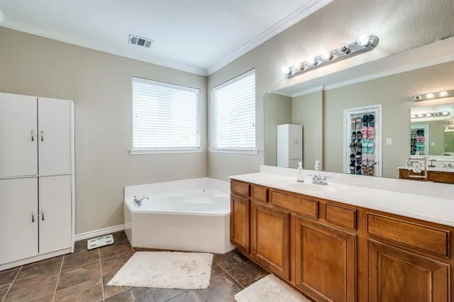 a en suite bathroom with a double vanity sink a mirror and a bathtub