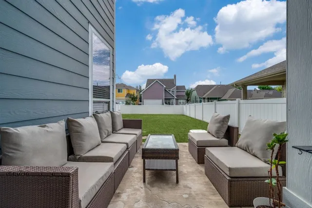 a view of a patio with couches and a fire pit and wooden fence
