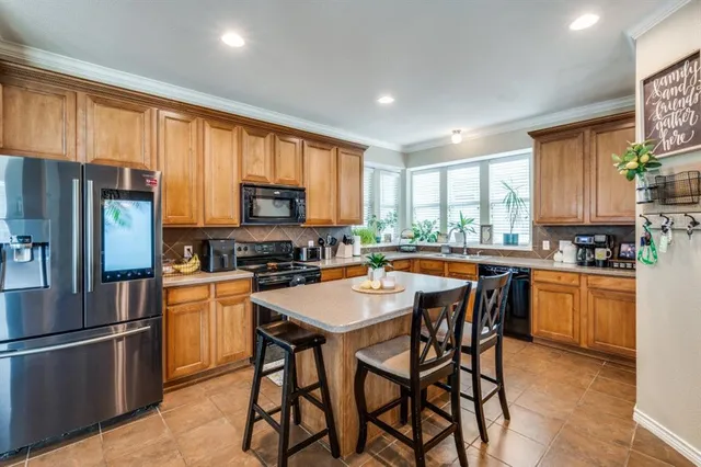 a kitchen with stainless steel appliances granite countertop a stove a refrigerator a sink a stove a dining table and chairs