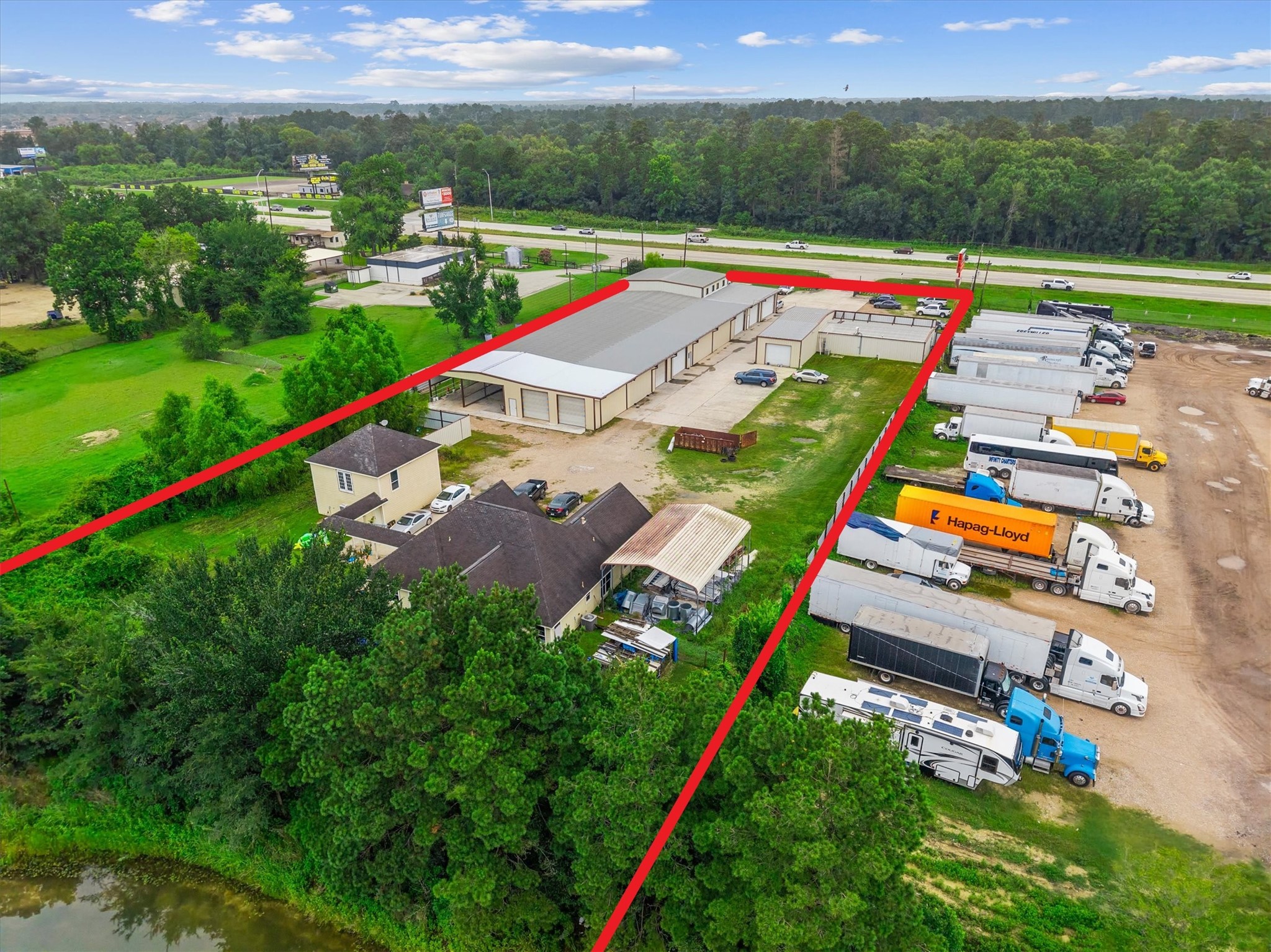 11066 Sh 242 Conroe, TX 77385 - Photo 4 of 21 This property features a large industrial facility with ample parking space, surrounded by greenery. It is conveniently located near a major highway, making it ideal for business operations requiring easy transportation access.