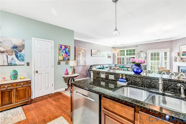 a living room with stainless steel appliances kitchen island granite countertop a sink and a cabinets