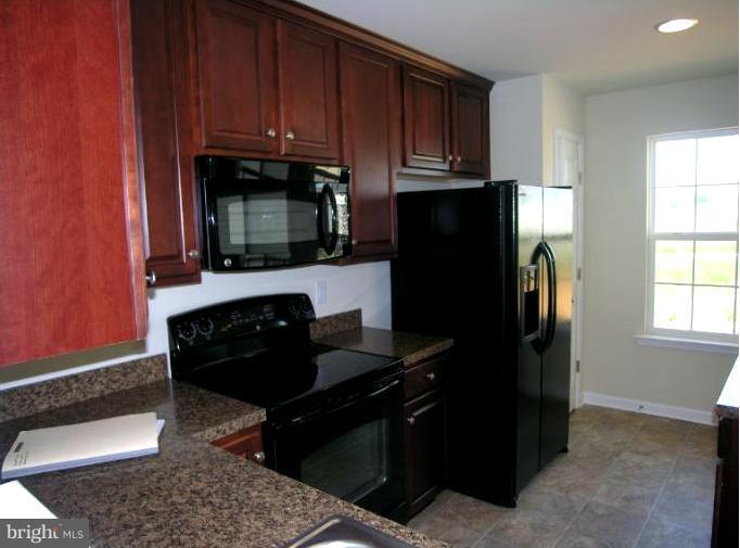 1159 Mare Street Ranson, WV 25438 - Photo 3 of 30 a kitchen with granite countertop wooden cabinets and a refrigerator