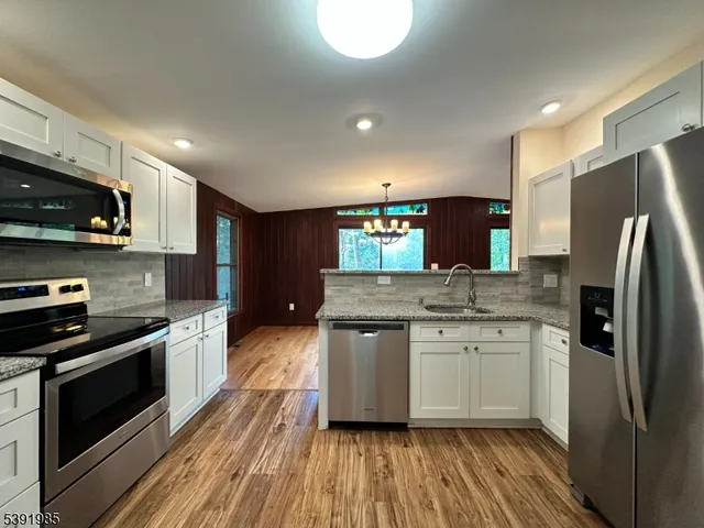 a kitchen with stainless steel appliances wooden floor sink stove and refrigerator