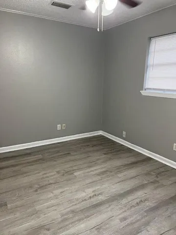 a view of a room with wooden floor fan and window