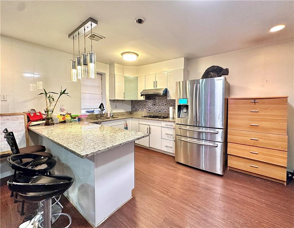 1944 85th Street Brooklyn, NY 11214 - Photo 2 of 10 a kitchen with stainless steel appliances kitchen island granite countertop a sink cabinets and wooden floor