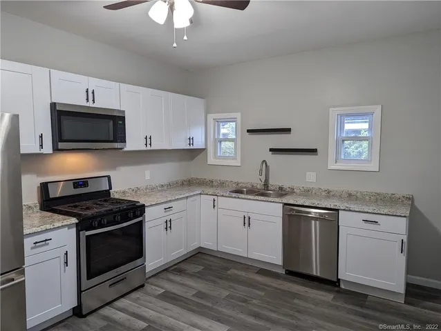 a kitchen with granite countertop stainless steel appliances a stove sink and microwave
