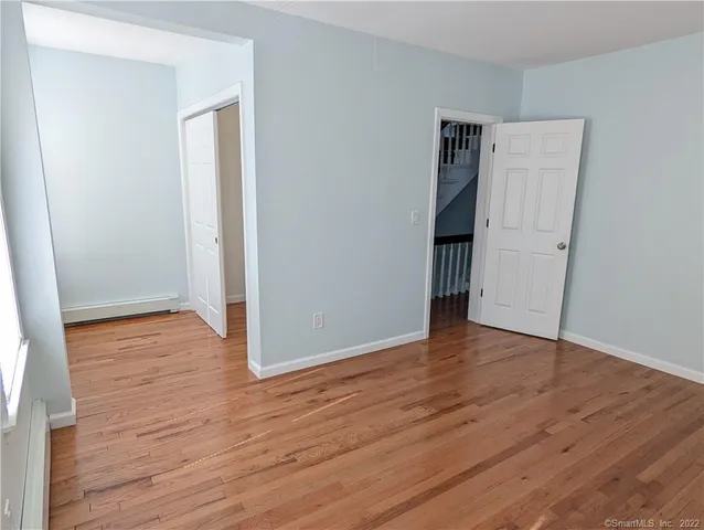 a view of an empty room with wooden floor and closet