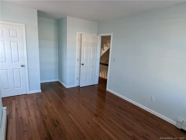 a view of an empty room with wooden floor and closet