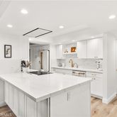 a kitchen with a sink a stove a refrigerator and white cabinets