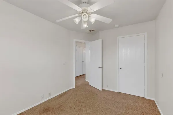 a view of an empty room and chandelier fan