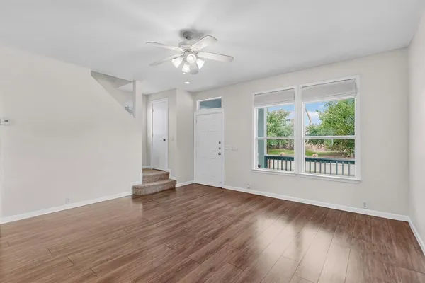 a view of an empty room with wooden floor and a window