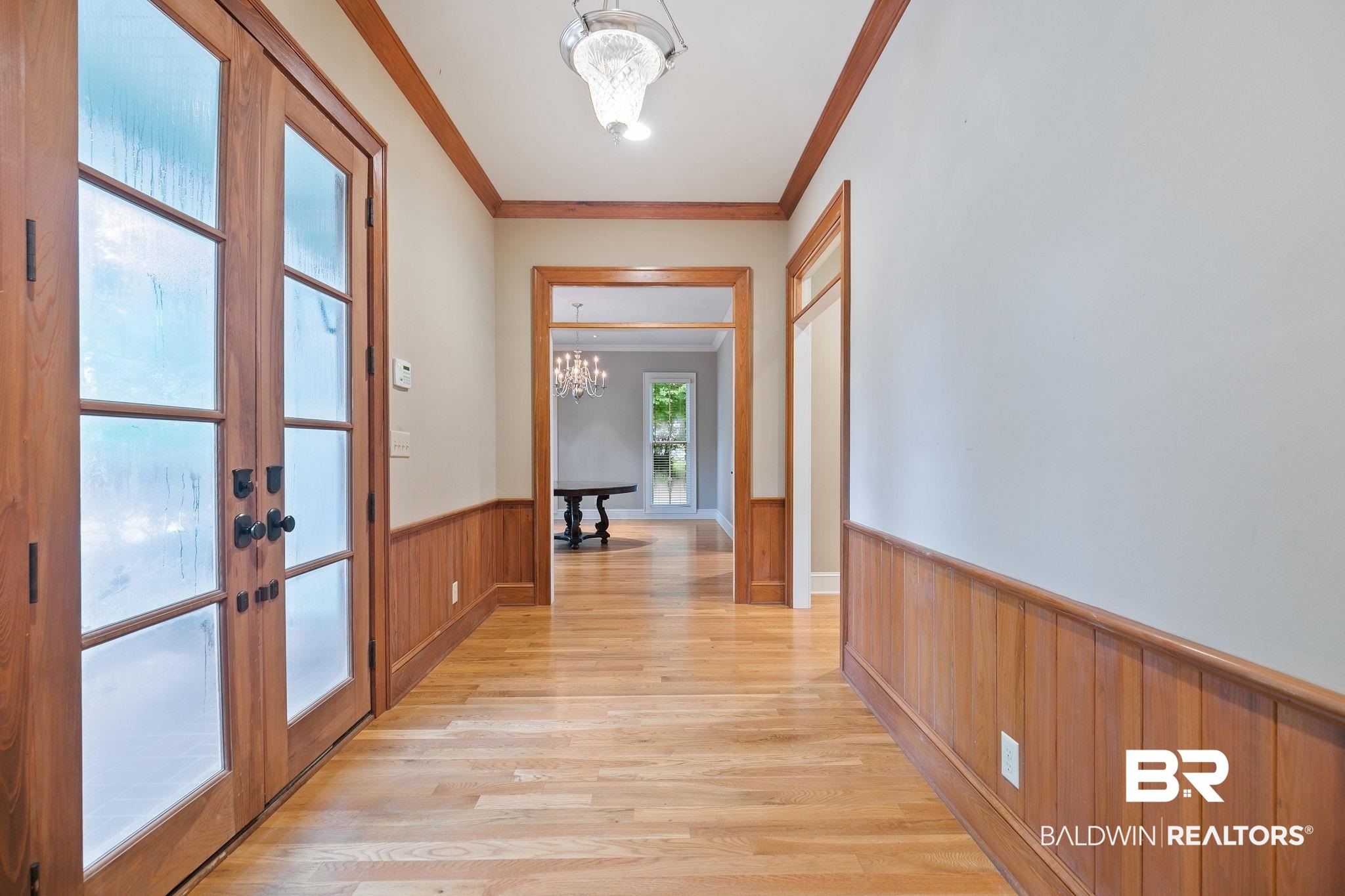 202 Beall Lane Daphne, AL 36526 - Photo 7 of 46 Hallway with an inviting chandelier, crown molding, french doors, and light hardwood / wood-style flooring
