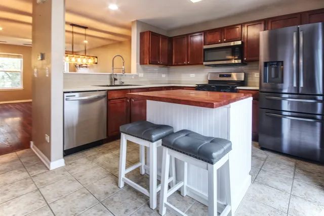 a kitchen with stainless steel appliances kitchen island granite countertop a sink stove and refrigerator