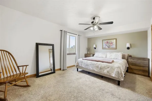 a spacious bedroom with a bed a chandelier and a dresser
