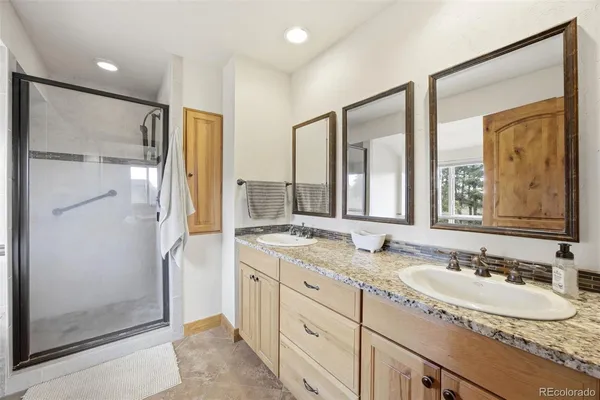 a bathroom with a granite countertop sink mirror shower and double