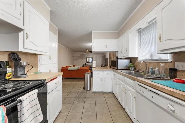 a kitchen with stainless steel appliances a sink dishwasher stove and white cabinets