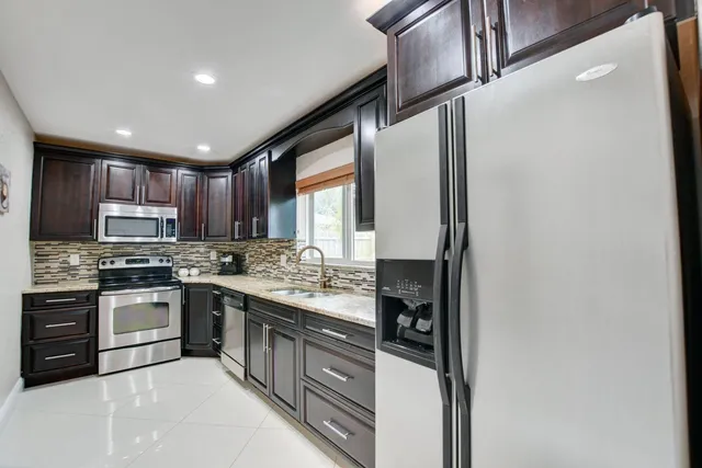 a kitchen with stainless steel appliances granite countertop a stove a sink and a refrigerator