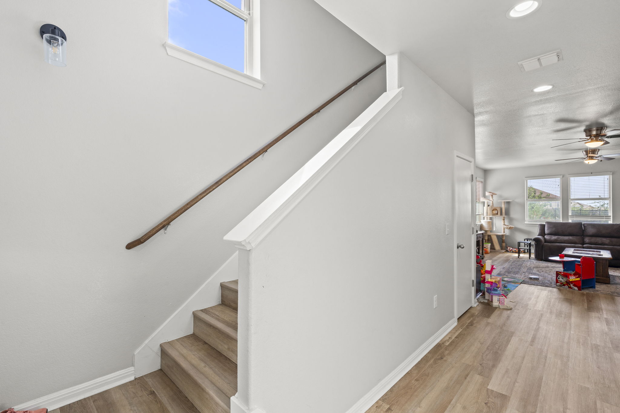 424 Wapiti Road Buda, TX 78610 - Photo 7 of 21 Modern interior staircase with light wood treads connects to an open-concept living area with ample natural light.