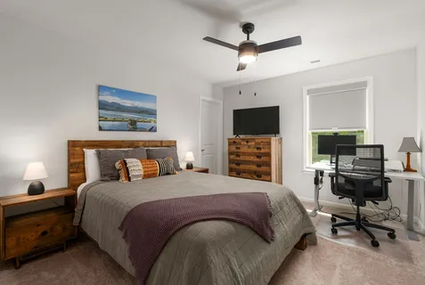 a bedroom with a large bed a flat tv screen and a dresser